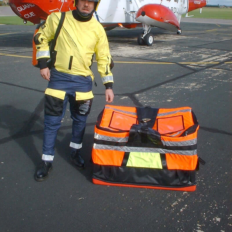 Helicopter load bag beside a person in safety gear, ready for offshore equipment transport.