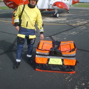 Helicopter load bag beside a person in safety gear, ready for offshore equipment transport.